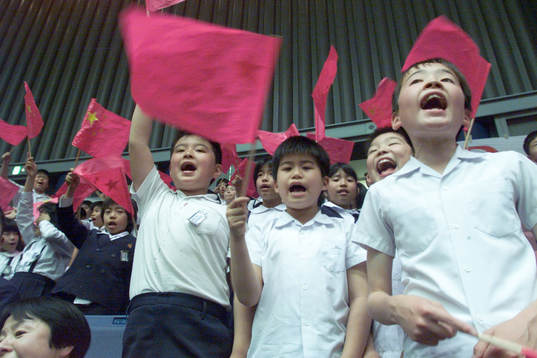 På läktaren finns det fullt med japanska skolbarn som