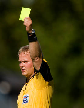Domare Erlendur Eiriksson, delar ut ett gult kort