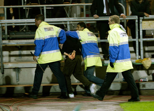 Ordningsvakter för ut en supporter som stormade planen.
