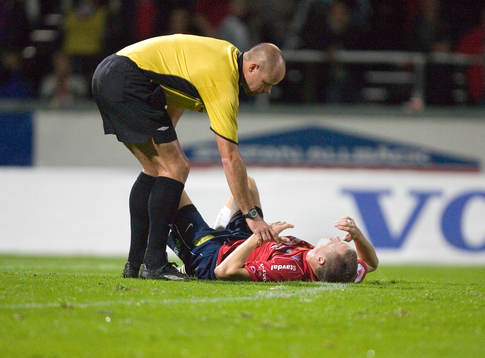 Martin Hansson, domare, kollar skadad spelare