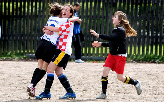 Tre tjejer kramar om varandra.  tjejfotboll, flickor,