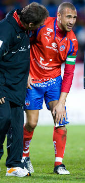 Henrik Larsson skadad, trycker en kylpåse mot knäet. Skada