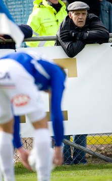 En gammaldags fotbollssupporter i keps följer med stort