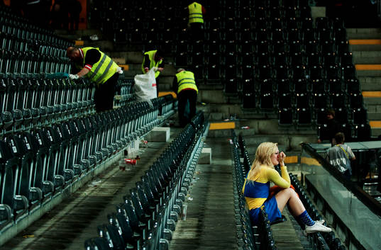 En ung svensk supporter sitter ensam kvar i arenan och