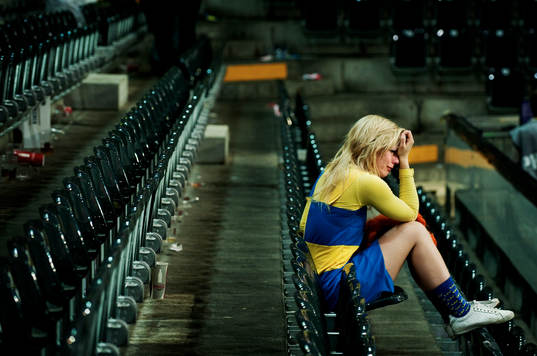 En ung svensk supporter sitter ensam kvar i arenan och