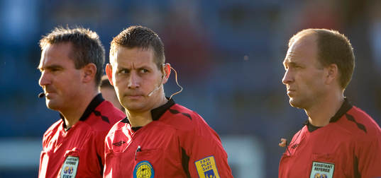 Magnus Ahlsén, domare omgiven av assisterande domare