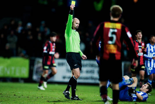 Stefan Johannesson, domare, delar ut ett gult kort