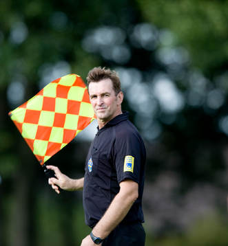 Assisterande domare vinkar med sin flagga