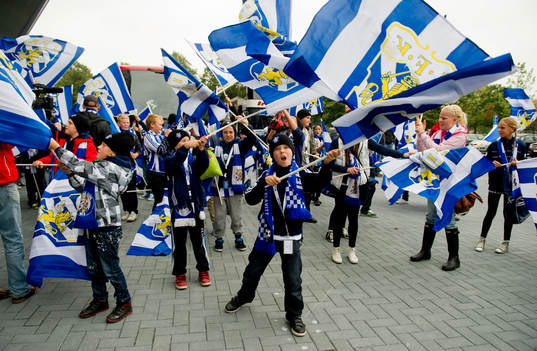 Young fellows på läktaren och utanför med flaggor