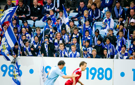 Young fellows på läktaren med flaggor