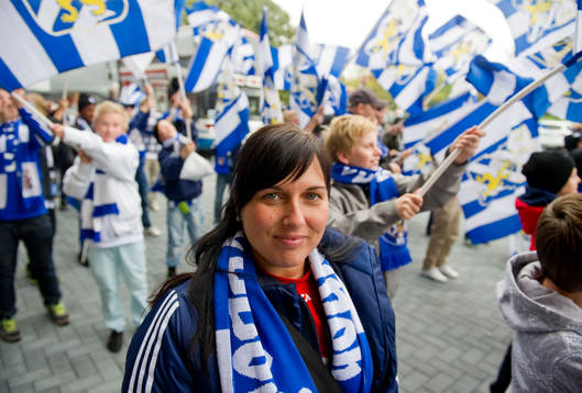 Young fellows på läktaren och utanför med flaggor