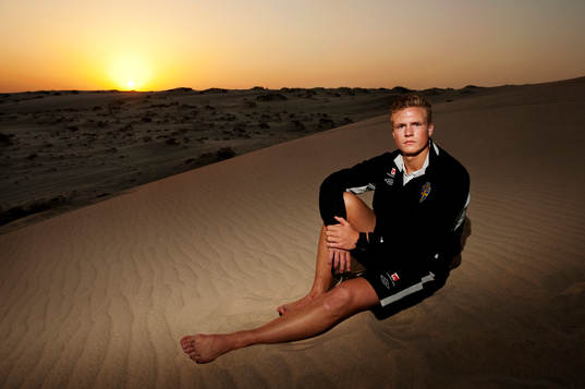 Oscar Hiljemark sitter på sanden när solen går ned i