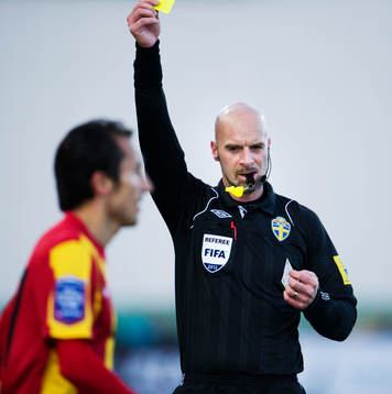 Stefan Johannesson, domare, delar ut ett gult kort, varning