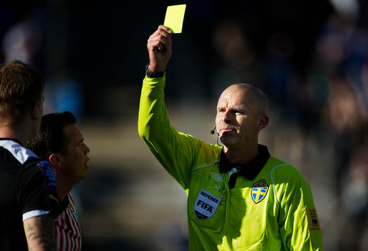 Michael Lerjéus, domare, delar ut ett gult kort. Varning