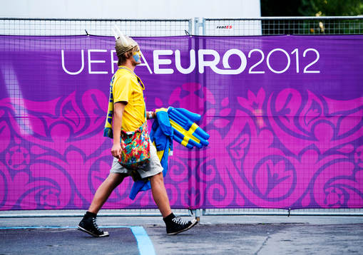 Ett svenskt fan, supporter passerar en UEFA Euro 2012-skylt