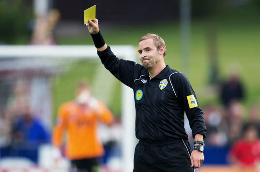 Jim Petersson, domare, delar ut ett gult kort