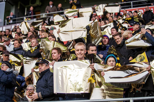 Publiken håller i guldpapper innan matchen