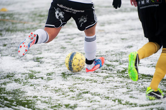 Fot, fotboll, fotbollsskor. Snö, snöig konstgräsplan.