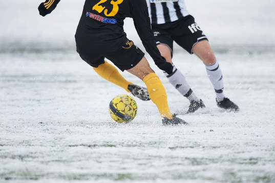 Fot, fotboll, fotbollsskor. Snö, snöig konstgräsplan.