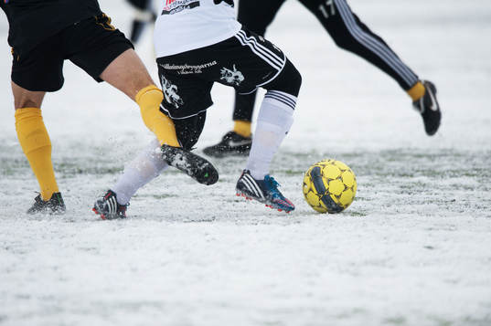 Fot, fotboll, fotbollsskor. Snö, snöig konstgräsplan.