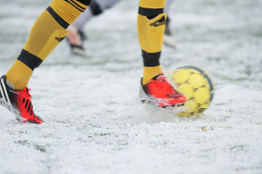 Fot, fotboll, fotbollsskor. Snö, snöig konstgräsplan.