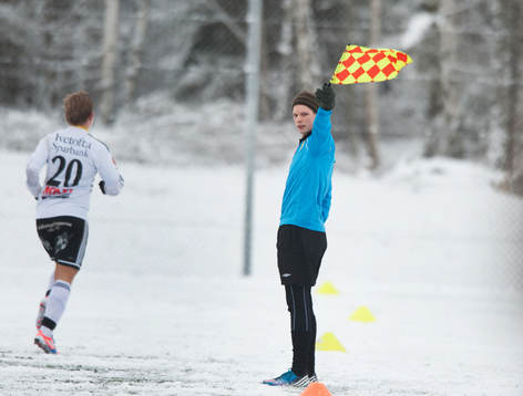 Assisterande domare, flagga. Snö, snöig konstgräsplan.