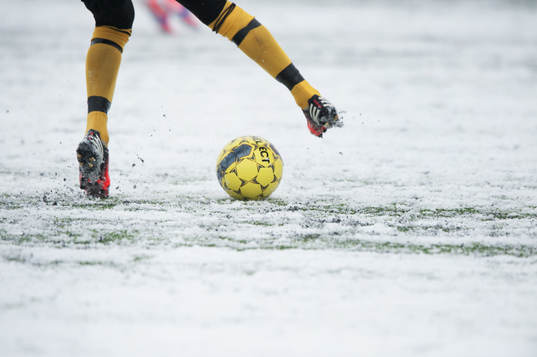 Fot, fotboll, fotbollsskor. Snö, snöig konstgräsplan.