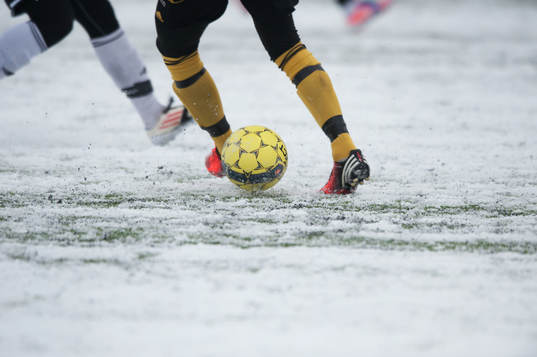 Fot, fotboll, fotbollsskor. Snö, snöig konstgräsplan.