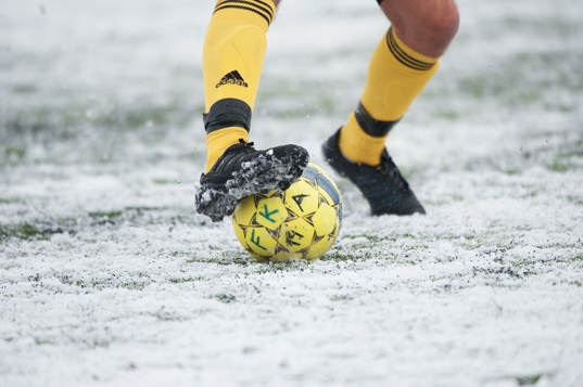 Fot, fotboll, fotbollsskor. Snö, snöig konstgräsplan.