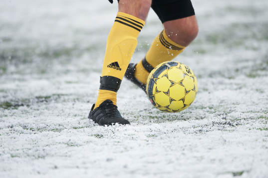 Fot, fotboll, fotbollsskor. Snö, snöig konstgräsplan.