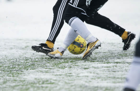 Fot, fotboll, fotbollsskor. Snö, snöig konstgräsplan.