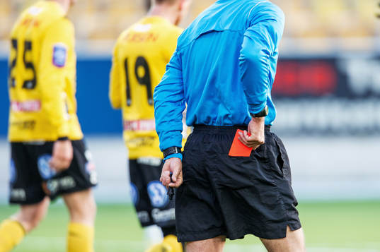 Domaren stoppar ner det röda kortet i bakfickan