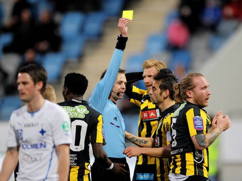 Johan Hamlin, domare, delar ut ett gult kort
