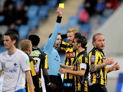 Johan Hamlin, domare, delar ut ett gult kort