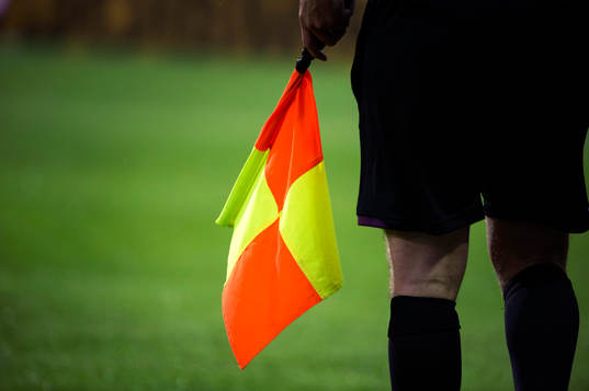 Assisterande domare håller hårt i sin flagga