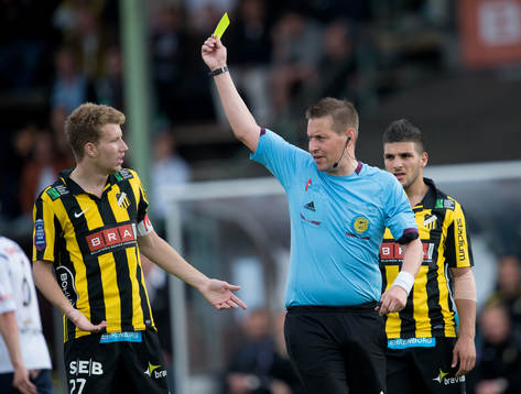 Domare Magnus Ahlsén visar det gula kortet för Simon