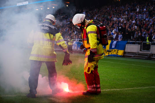 Räddningsvärdar tar hand om en bengaleld som kastats in