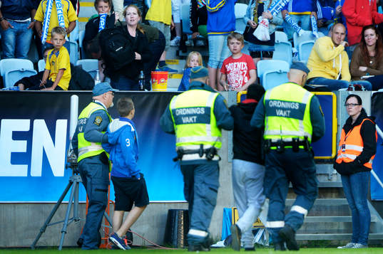 Två åskådare leds bort av ordningsvakter