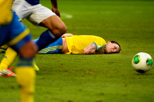 Sveriges Zlatan Ibrahimovic grimaserar liggande på planen