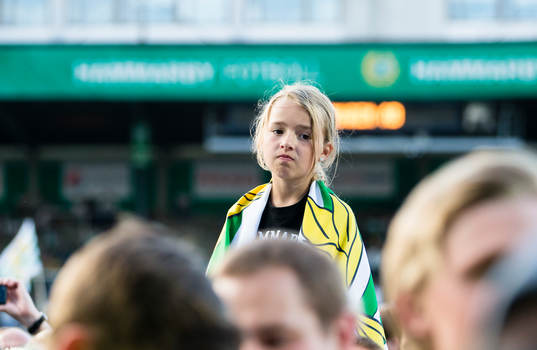 En flicka sitter på axlarna i publikhavet på gräsmattan