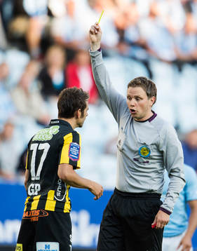 domare Markus Strömbergsson ger ett gult kort till