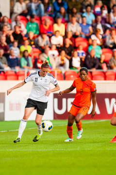 Tysklands Anja Mittag springer med bollen. Hollands Dyanne