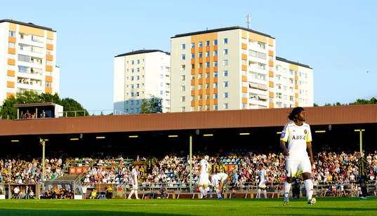 s AIK:s Martin Kayongo Mutumba nedanför höghusen på