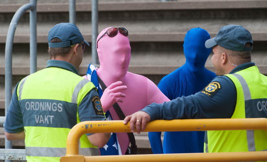 Supporter, gummiklädd, samspråkar med ordningsvakter i