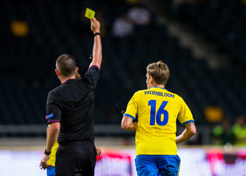 Domare Michael Oliver delar ut ett gult kort till Sveriges