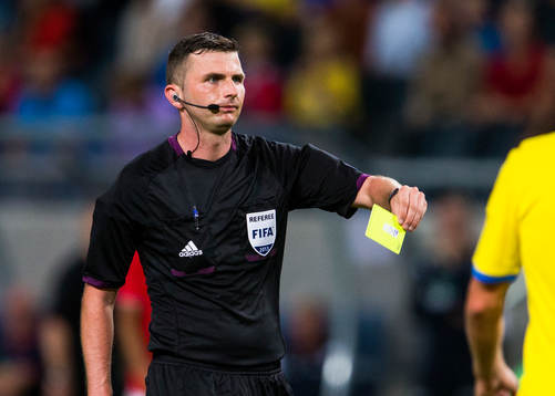 Domare Michael Oliver delar ut ett gult kort
