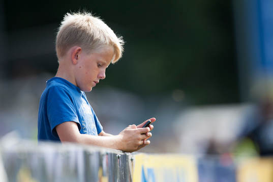 Pojke kollar mobiltelefonen mitt