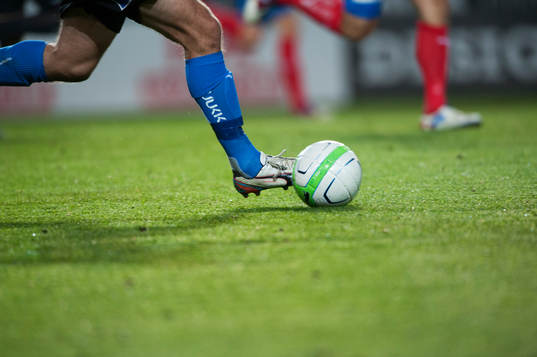 Bollen drivs fram över det blöta gräset, fotbollssko, i