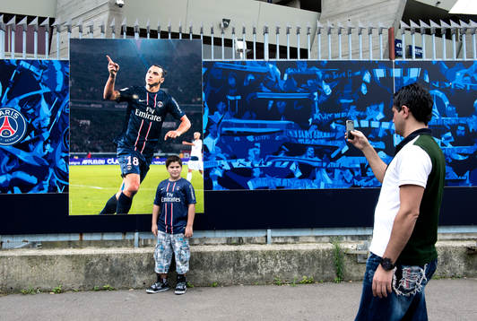 En ung supporter blir fotograferad framför en bild av