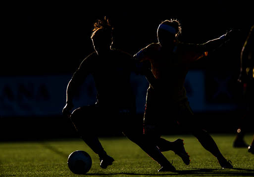 Siluett på två fotbollsspelare i kamp om bollen